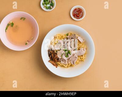 Hackfleisch Noodle in einer Schüssel mit Suppe, Chilisauce und Frühlingszwiebeln Draufsicht auf Holztisch Stockfoto