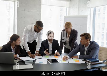 Gruppe fokussierter junger seriöser multirassischer Kollegen, die Papierkram machen. Stockfoto