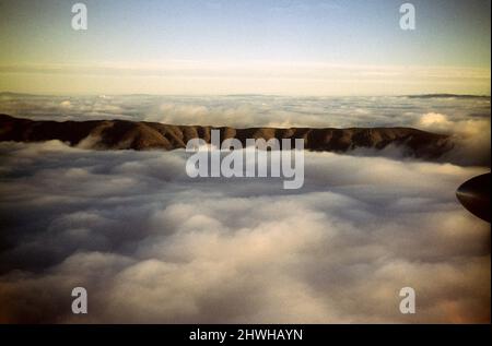 Schräge Winkelansicht des Bergrückens aus der Wolkenschicht, Standort unbekannt, Australien 1956 Stockfoto