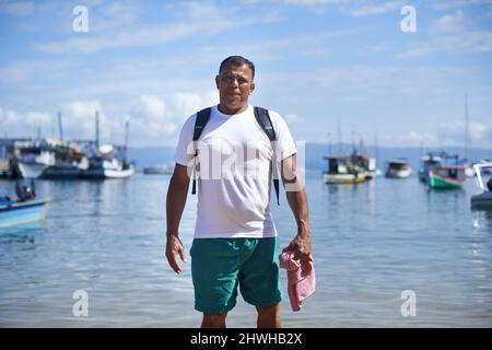 Angeln ist mein Leben. Porträt eines Fischers, der im seichten Wasser im Hafen steht. Stockfoto