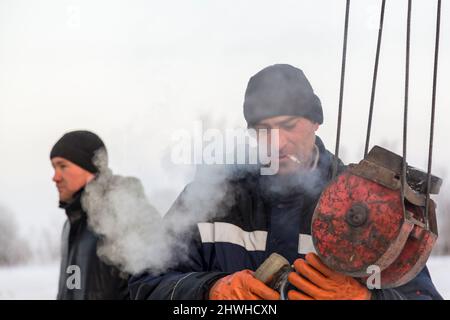 Der Schleuder zieht eine Bandschlinge am Haken eines LKW-Krans an Stockfoto