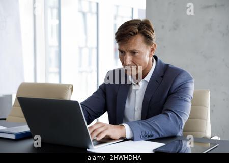 Fokussierter Geschäftsmann im mittleren Alter von 40s Jahren, der am Computer arbeitet. Stockfoto