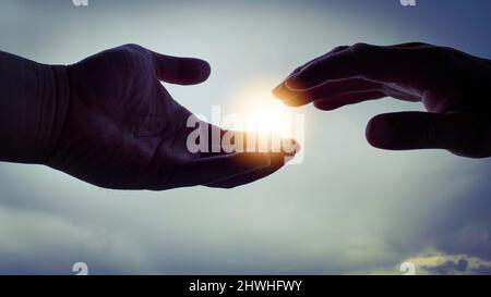 Zwei Hände versuchen, sich zu einem hellen, leuchtenden Licht zu strecken. Stockfoto