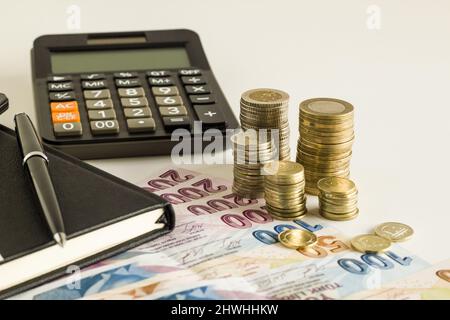 Türkische Lira Banknoten, Notizbuch, Stift, Münzen und ein Taschenrechner auf weißem Hintergrund Stockfoto