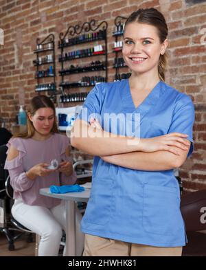 Junge lächelnde Mädchen Manikuristin steht in modernen Nagelstudio Stockfoto