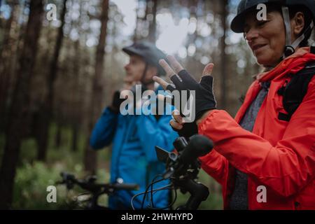 Ältere Biker, die am Herbsttag im Wald Fahrradhelm und Handschuhe anziehen. Stockfoto