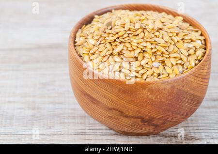 Die Goldflachskerne in einer Holzschale auf braunem Hintergrund. Stockfoto