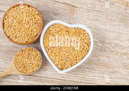 Die Goldflachskerne in einer Holzschale auf einem hölzernen Hintergrund. Stockfoto