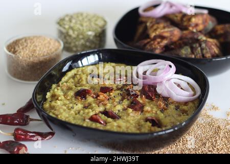 Ein Topf Zubereitung mit kodo Hirse, Mungbohnenlinse. Allgemein bekannt als kodo Hirse khichdi in Indien. Serviert mit gebratenem Makrelenfisch und Zwiebelrinne Stockfoto