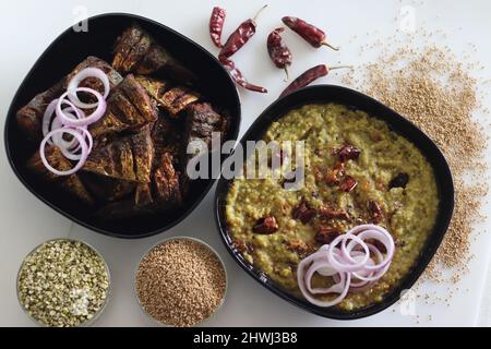 Ein Topf Zubereitung mit kodo Hirse, Mungbohnenlinse. Allgemein bekannt als kodo Hirse khichdi in Indien. Serviert mit gebratenem Makrelenfisch und Zwiebelrinne Stockfoto