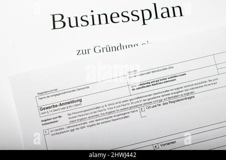 Das deutsche Standardformular für die Geschäftsanmeldung in deutscher Sprache bei der Stadt oder Gemeinde liegt auf einem Businessplan für den Start der Selbständigung Stockfoto