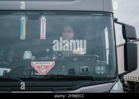 Lehrte, Deutschland. 06. März 2022. LKW-Fahrer Petr aus Weißrussland sitzt in seinem LKW auf dem Highway A2 Dienstgebiet lehrte. An seiner Windschutzscheibe hat Petr die ukrainische Flagge gehängt, um seine Solidarität und Unterstützung für die Ukraine auszudrücken. Petr zog wegen politischer Verfolgung in seinem Heimatland Weißrussland ins benachbarte Polen. Viele ukrainische Lkw-Fahrer sagen, dass sie in ihre Heimat zurückkehren, um vor Ort zu helfen. Quelle: Ole Spata/dpa/Alamy Live News Stockfoto