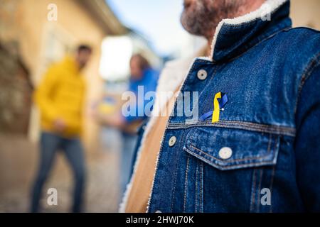 Demonstranten mit ukrainischen blauen und gelben Bändern protestieren auf der Straße gegen den Krieg in der Ukraine Stockfoto