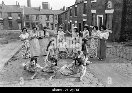 Frauen aus Manila, die in einer Mühle in Rochdale, Lancashire, arbeiten, zeigen in den Kopfsteinpflasterstraßen von Rochdale nationale Tänze. 20.. Juli 1972. Stockfoto