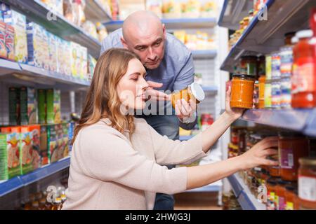 Positives Familienpaar im Laden, in dem das Glas aufbewahrt wird Stockfoto