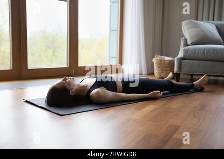 Junge Frau hört meditative Musik über Ohrstöpsel, die sich nach dem Yoga entspannen Stockfoto