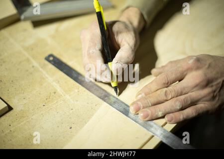 Markierung auf Lineal mit Bleistift. Zeichnen einer Linie auf dem Baum. Hände des Zimmermanns. Projekt erstellen. Stockfoto