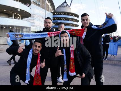 Vor dem Premier League-Spiel im Etihad Stadium, Manchester, posieren Fans draußen mit Halb- und Halbstüchern. Bilddatum: Sonntag, 6. März 2022. Stockfoto