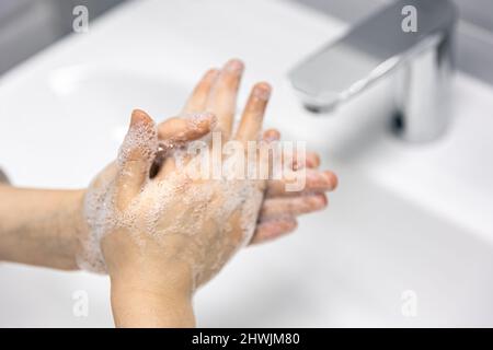 Aus nächster Nähe wäscht das Kind seine Hände im Badezimmer. Stockfoto