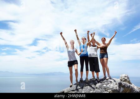 An die Spitze. Aufnahme einer Gruppe von Freunden, die sich freuen, nachdem sie den Gipfel eines Berges erreicht haben. Stockfoto