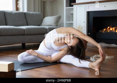 Frau sitzt auf der Matte im Wohnzimmer führen Yoga Asanas Stockfoto