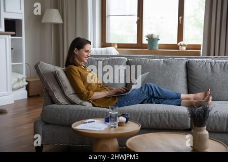 Seitenansicht Frau sitzt auf dem Sofa SMS-Nachricht mit Laptop Stockfoto