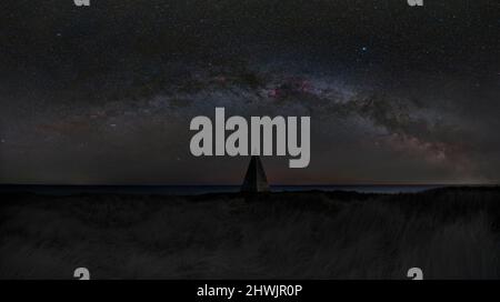 Ein launiges Bild der Milchstraße, die sich über den Emmanuel-Kopf-Tagesstempel auf Lindisfarne (Heilige Insel), Berwick-upon-Tweed, spannt Stockfoto