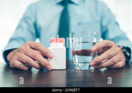 Der Geschäftsmann zeigte auf dem Tisch Flaschenpille und Wasser. Stockfoto