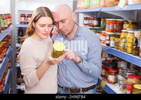 Erwachsenes Paar, das konservierte Waren wählt Stockfoto