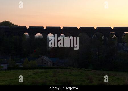 Silhouette eines Güterzuges mit Zuschlagstofftrichtern, der die Kapelle Milton Viaduct, Chinley, Derbyshire überquert Stockfoto