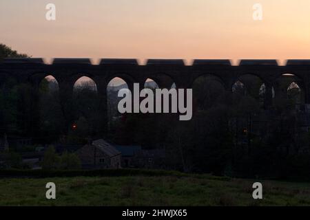 Silhouette eines Güterzuges mit Zuschlagstoffen Trichter überqueren Kapelle Milton Viaduct, Chinley, Derbyshire mit Bewegung Unschärfe Stockfoto