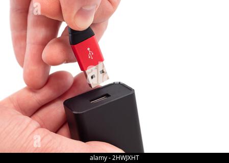 Schließen Sie das usb-Kabel mit den Händen an die Buchse auf einem weißen Hintergrund an. USB-Verbindung Stockfoto