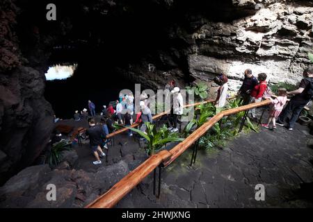 Touristen, die im Vulkantunnel jameos del agua, lanzarote, kanarische Inseln, spanien, Treppen vom Jameo chico zum Gezeitensee hinunterlaufen Stockfoto