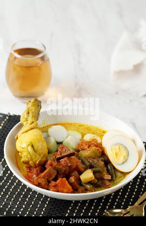 Ketupat oder lontong sayur, indonesische Küche, spezielles Gericht, das bei der Eid Mubarak Eid Fitr-Feier serviert wird. Mit Tee servierte Stockfoto