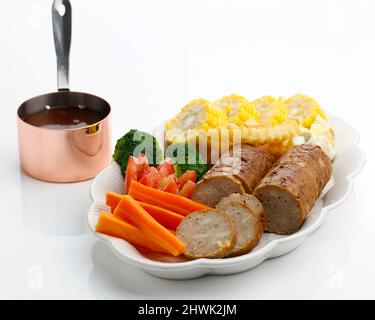 Gebackener Hackbraten mit gekochten Eiern und Gemüse, serviert mit Pilzsauce vom Grill, isoliert auf weißem Hintergrund. Stockfoto