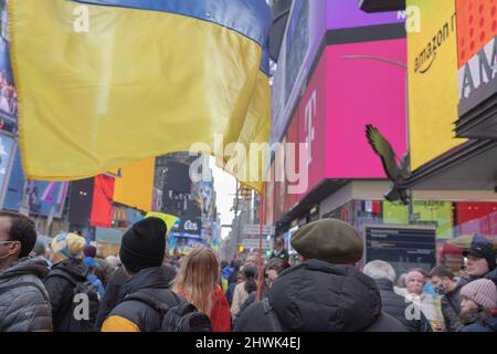 NEW YORK, NY – 5. März 2022: Während eines Protestes gegen die russische Invasion in die Ukraine hält eine Person auf dem Times Square eine ukrainische Flagge. Stockfoto