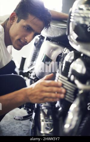 Bewundernd seine Schönheit. Ein hübscher junger Mann bewundert sein Motorrad. Stockfoto