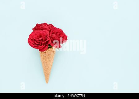 Rote Rosen in Eiskegel auf hellblauem Hintergrund. Muttertag, Valentinstag, Geburtstag, Sommerkonzept. Flach liegend, Platz für Text kopieren. Stockfoto