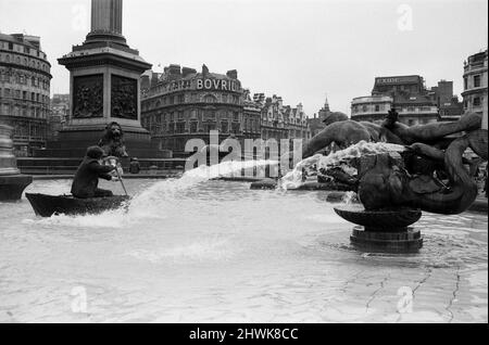 Coracle Fishermen in London. Einer der Fischer paddelt zum Interesse der Besucher sein Corakel um den Trafalgar Square Brunnen. 1.. April 1972. Stockfoto