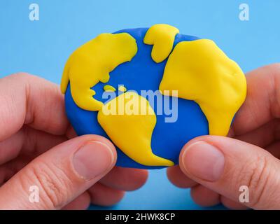 Eine Frau, die den Planeten Erde in den Händen hält. Der Planet Erde besteht aus Fimo. Stockfoto