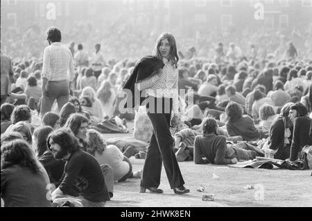 Ein langhaariger Musikfan, Jack über seine Schulter, wandert durch die riesige Menge und das Publikum, das das Oval Pop Festival, Oval Cricket Ground, South London, genießt. Im Spätsommer 1972 an dem Tag gewann Rod Stewart den besten männlichen Sänger 1972, Emerson Lake und Palmer 7 Preise, Maggie Bell und Brian Eno haben ebenfalls Preise gewonnen. Beachten Sie auf diesem Bild die Dose von Fanta und die Schachtel mit Ritz-Keksen auf dem Boden. Klassisches Essen aus dem Jahr 1970s. Das Festival wurde vom Music Magazine Melody Maker Picture Taken 30.. September 1972 gesponsert Stockfoto