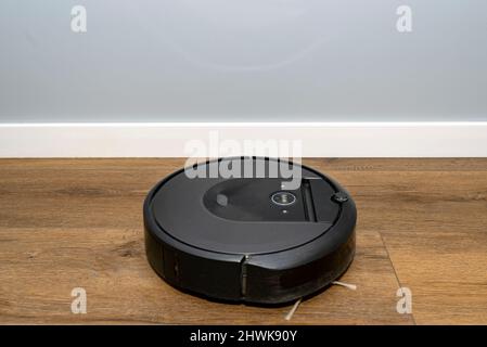 Ein moderner Roboter-Staubsauger, der auf Vinylplatten läuft, ein autonomer Reinigungsroboter. Stockfoto