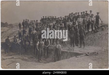 Grabengraben, erster Weltkrieg. Foto einer großen Gruppe britischer Soldaten, die mit Pik und Schubkarren an einem teilweise ausgegrabenen Graben und auf einem Erdhügel posieren Stockfoto