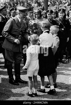 Kinder überbringen Adolf Hitler nach seiner Ankunft auf dem Festivalgelände Blumen. Grundsteinlegung Volkswagenfabrik 26. Mai 1938. Stockfoto