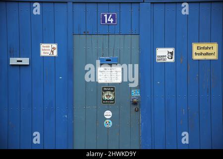 Blaues Holztor und Tür mit vielen Hinweisschildern in Sindlingen, Hessen, Deutschland Stockfoto