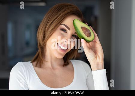 Junge kaukasische Frau mit Avocado am Kopfporträt Stockfoto