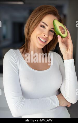 Junge fröhliche kaukasische Frau mit Avocado-Porträt Stockfoto