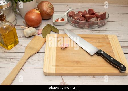 Zubereitung von Speisen für die Herstellung von Gulasch. Alles auf einem Holztisch, Blick von oben. Stockfoto