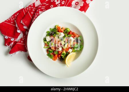 Türkischer frischer Coban-Salat in einem Gericht isoliert auf buntem Tischtuch Draufsicht auf grauem Hintergrund gemischter Salat Gurke, Limette und Tomate Stockfoto