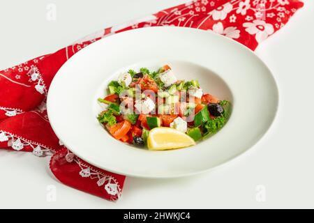 Türkischer frischer Coban-Salat in einem Gericht isoliert auf buntem Tischtuch Draufsicht auf grauem Hintergrund gemischter Salat Gurke, Limette und Tomate Stockfoto